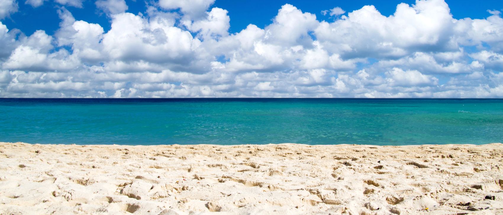 White sand and turquoise water under a sky of big white clouds